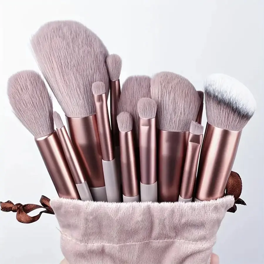 Thirteen piece pink makeup brush set arranged with storage pouch